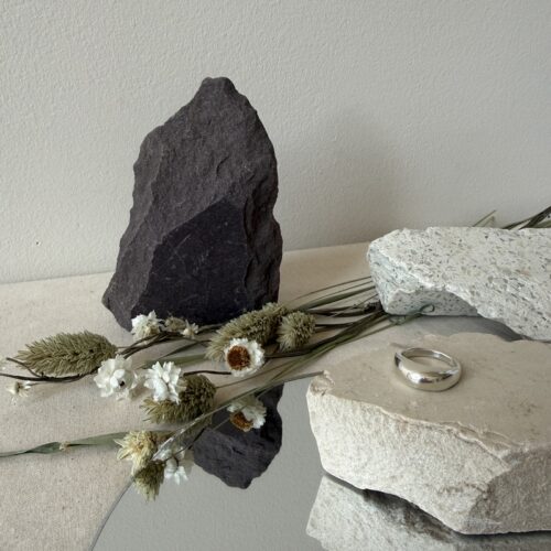 sterling silver dome ring lost wax cast work on neutral stone with mirror underneath with rocks and dried floral background against neutral wall