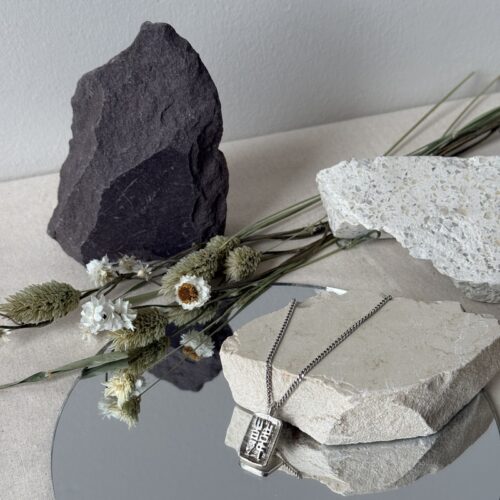 HON chinese character sterling silver pendant lost wax cast work on neutral stone with mirror underneath with rocks and dried floral background against neutral wall