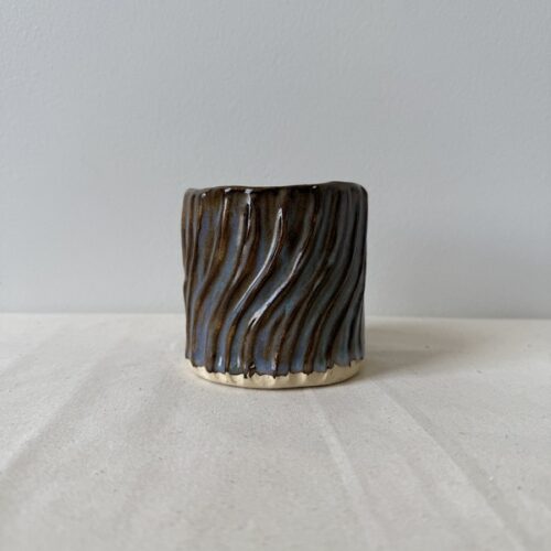 ceramic japanese teacup with waves in randys red brown glaze on neutral linen fabric and cream wall background by studio hon handbuilding pottery